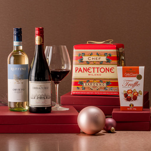 Italian an chilean wine bottles with a red wine glass, chocolate truffles and Italian Panettone.